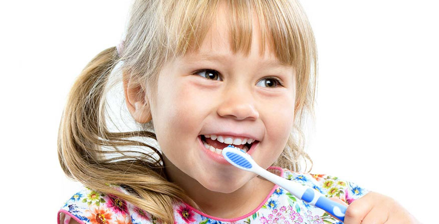 Young girl smiling with her mouth open and holding up a tooth brush.