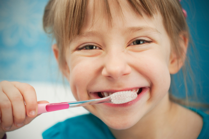 Girl smiling while brushing her teeth.